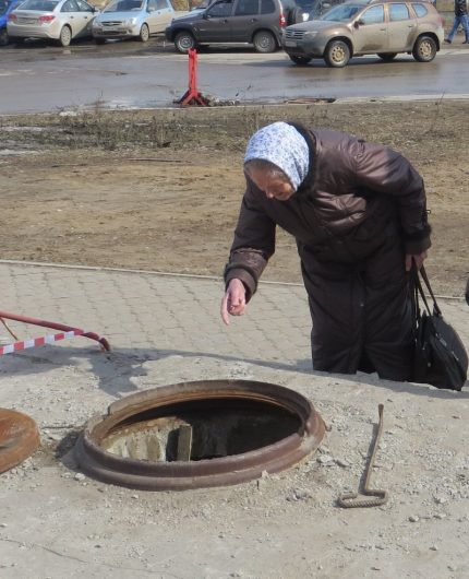 O femeie în vârstă se uită în canalizare